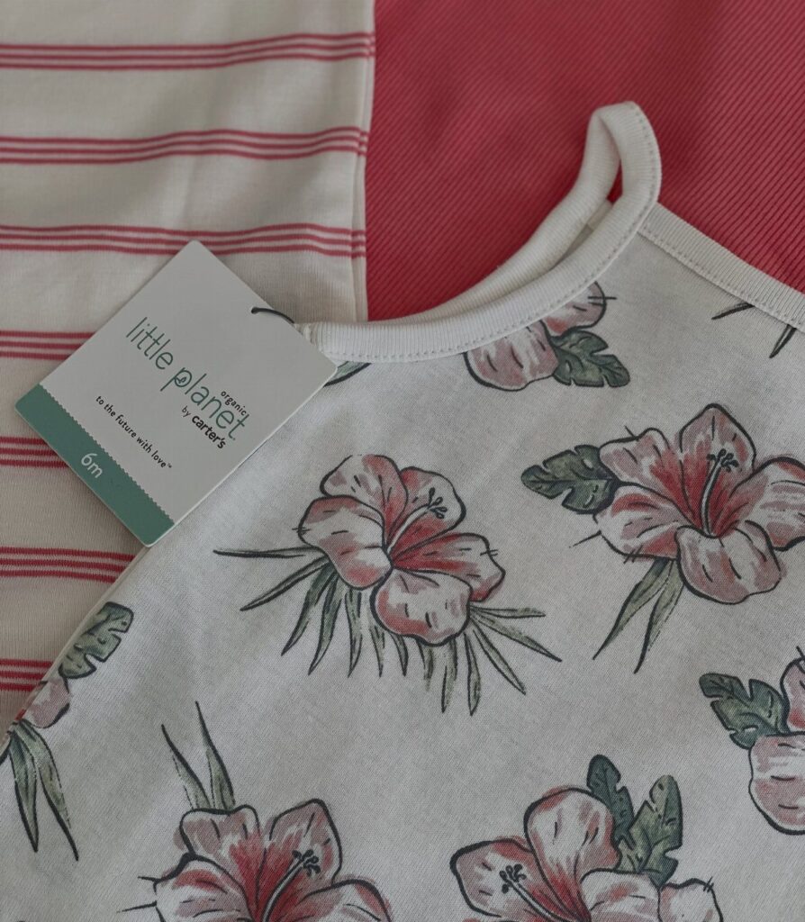 White infant clothes with hibiscus prints and red stripes featuring a Little Planet tag.