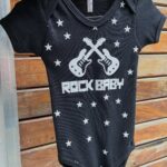 Black infant bodysuit with white stars, crossed guitars, and ROCK BABY text.